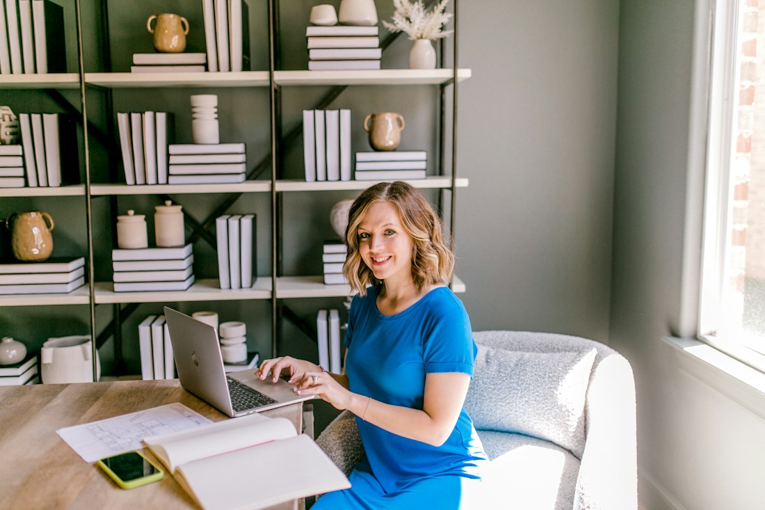 Junge Frau im blauen Kleid arbeitet am Laptop